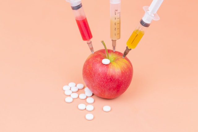 red apple beside clear plastic bottle