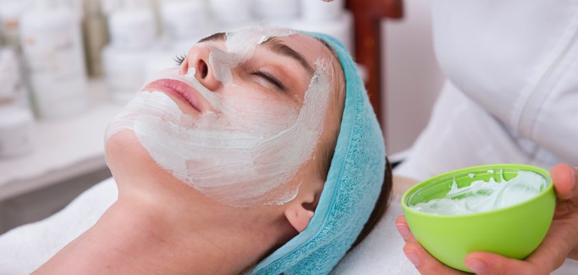 woman lying on blue towel with white cream on face